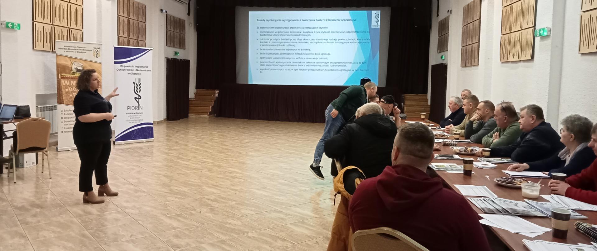 Wystąpienie inspektora Wojewódzkiego Inspektoraty Ochrony Roślin i Nasiennictwa w Olsztynie. Prelegent tłumaczy coś uczestnikom wykładu w zakresie zagadnień fitosanitarnych. 