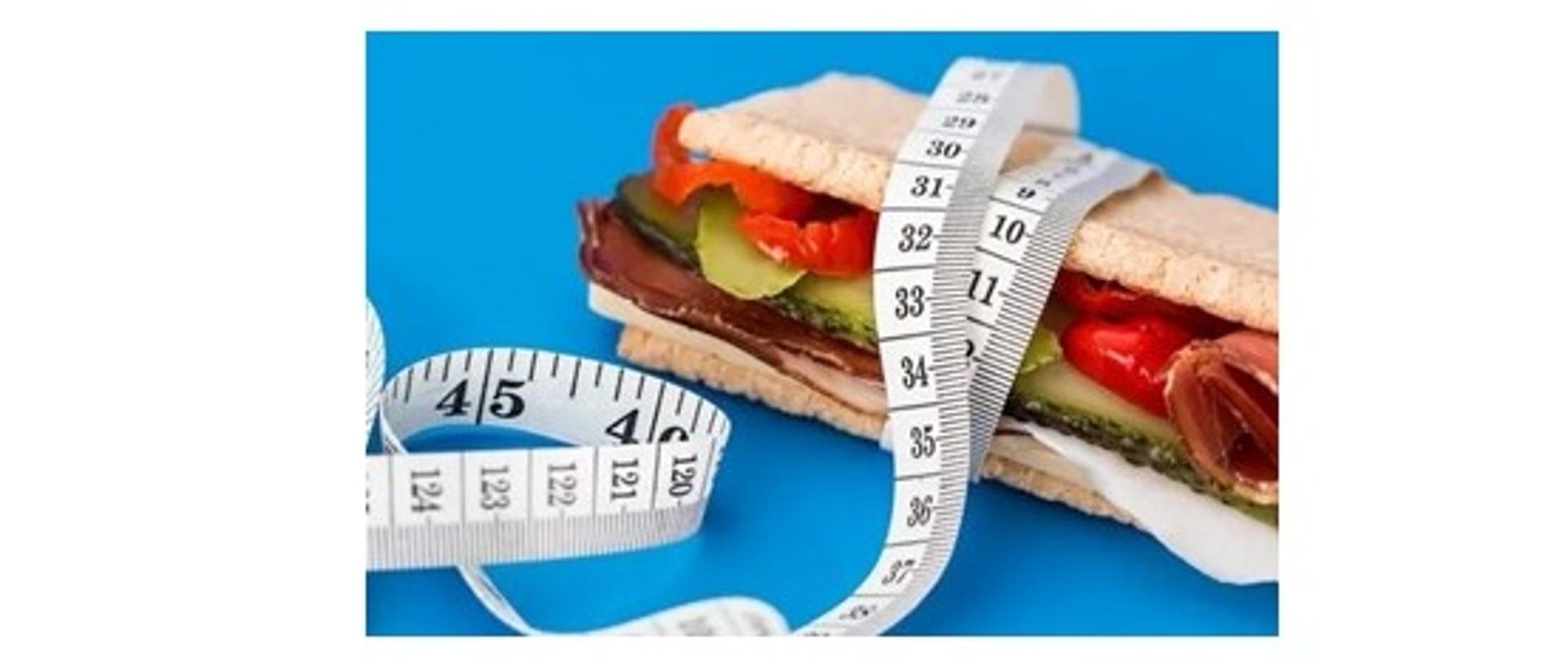 Na niebieskim tle znajduje się kanapka przewiązana centymetrem krawieckim.