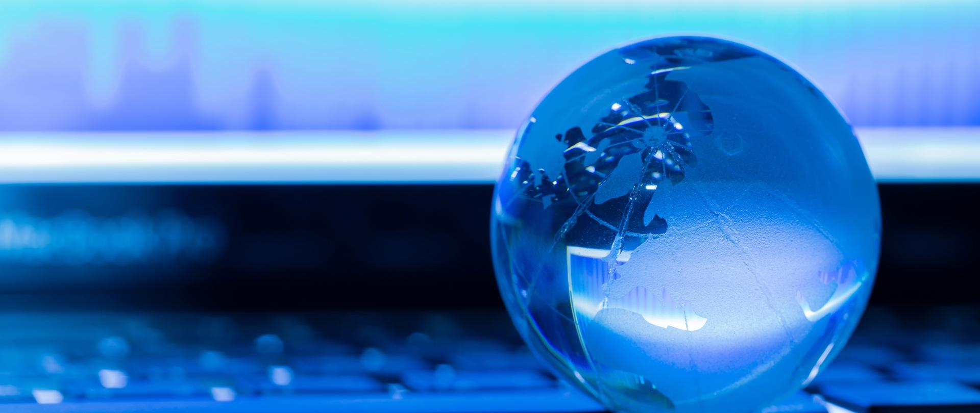 Koncepcja biznesowa szklanego świata na klawiaturze laptopa na tle wykresu