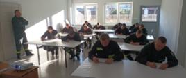 Zdjęcie przedstawia strażaków ratowników OSP podczas egzaminu pisemnego. 