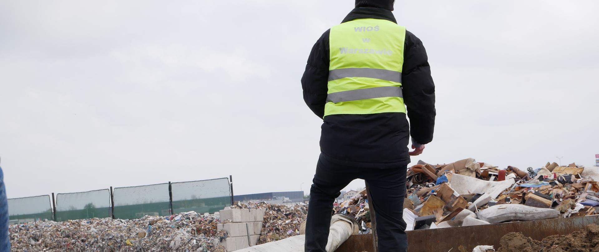 Inspektor Wojewódzkiego Inspektoratu Ochrony Środowiska w Warszawie prowadzi oględziny miejsca nielegalnego gromadzenia odpadów.