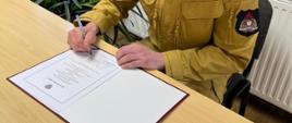 Strażak podczas podpisywania aktu ślubowania