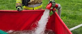 Strażak napełniania czerwony zbiornika buforowy w tle akwen wodny