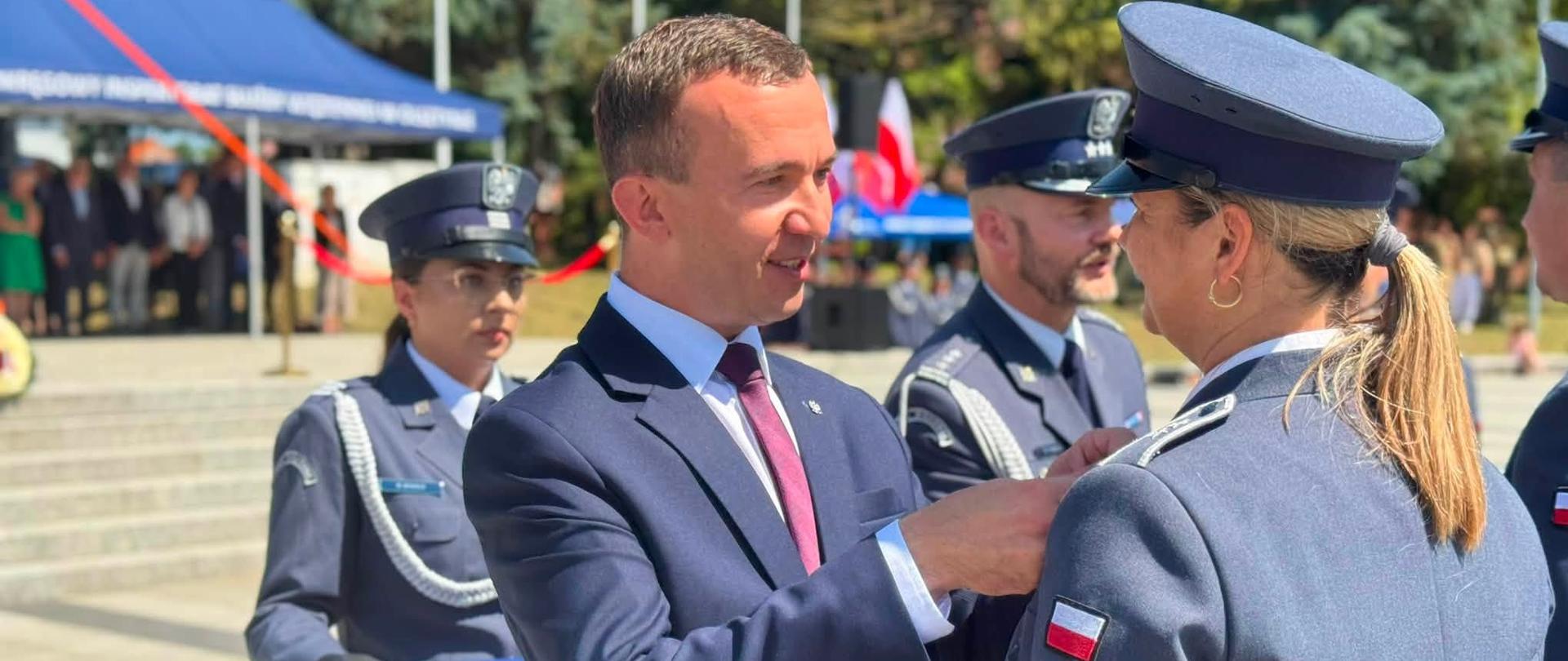 mężczyzna w garniturze, wicewojewoda, przypina odznaczenie policjantce 