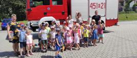 Dzieci z przedszkola wraz z opiekunami pozują na tle samochodu pożarniczego