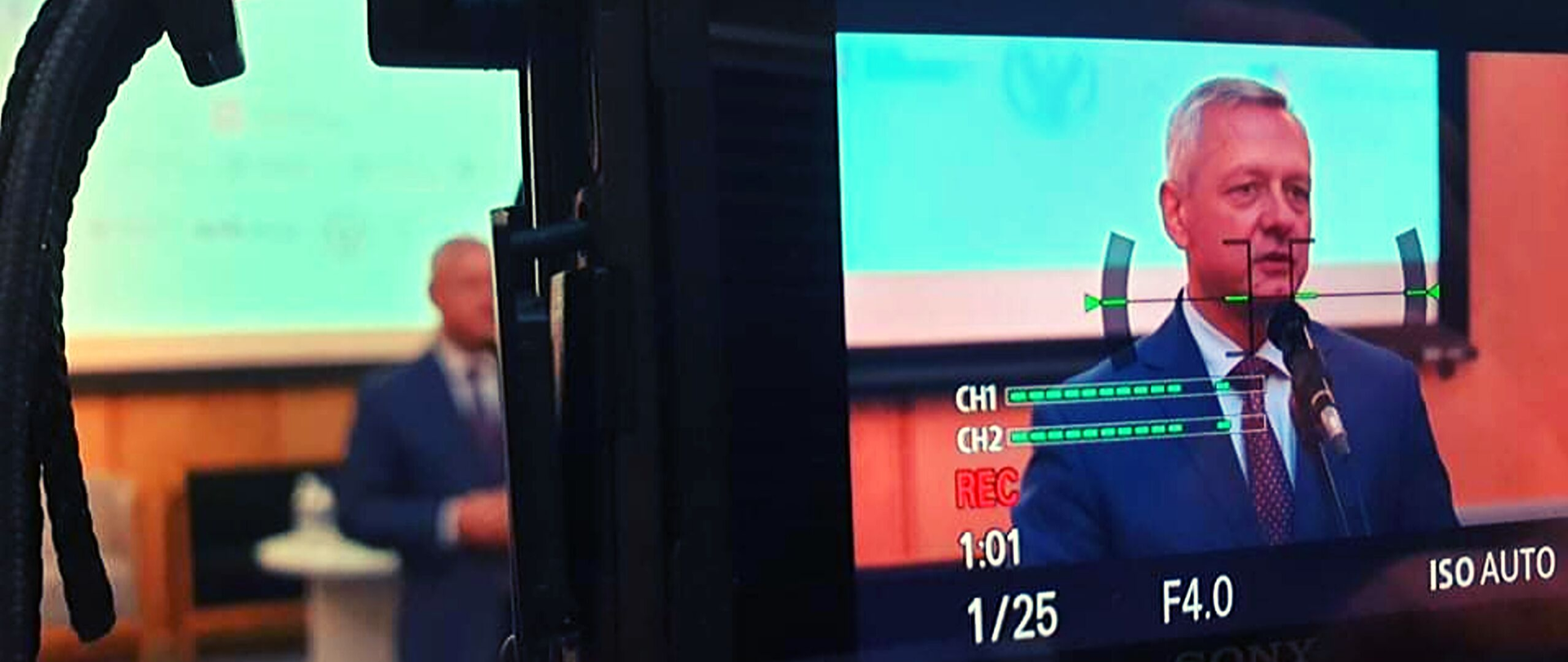 Minister Marek Zagórski podczas przemówienia. Widać postać na ekranie aparatu