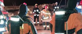 Zdjęcie przedstawia strażaków oraz urządzenie HDS podczas opuszczania betonowej płyty do szamba