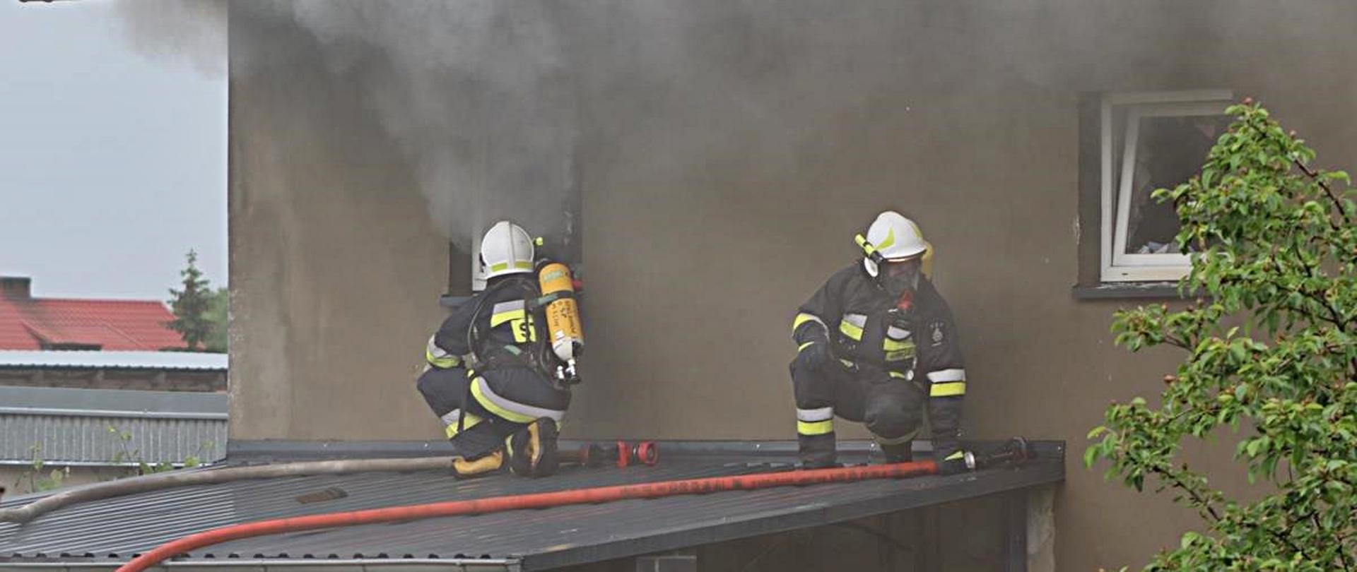 Budynek. strażacy na dachu, dym z okien