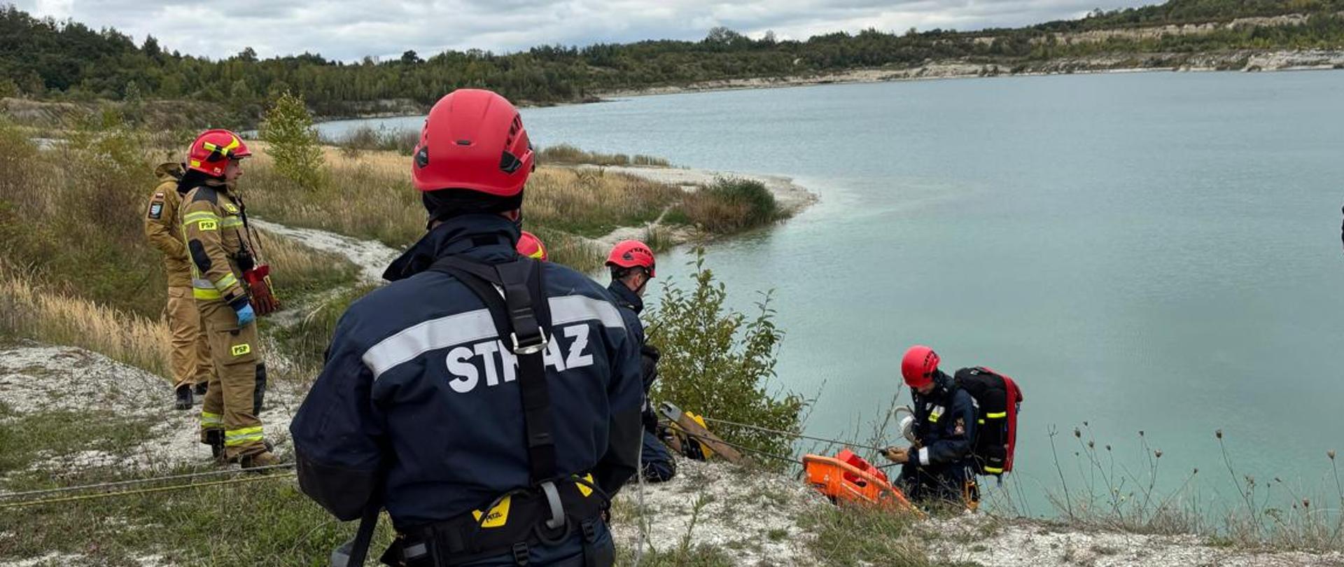 Strażacy na tle zbiornika wodnego na terenie byłej kopalni.