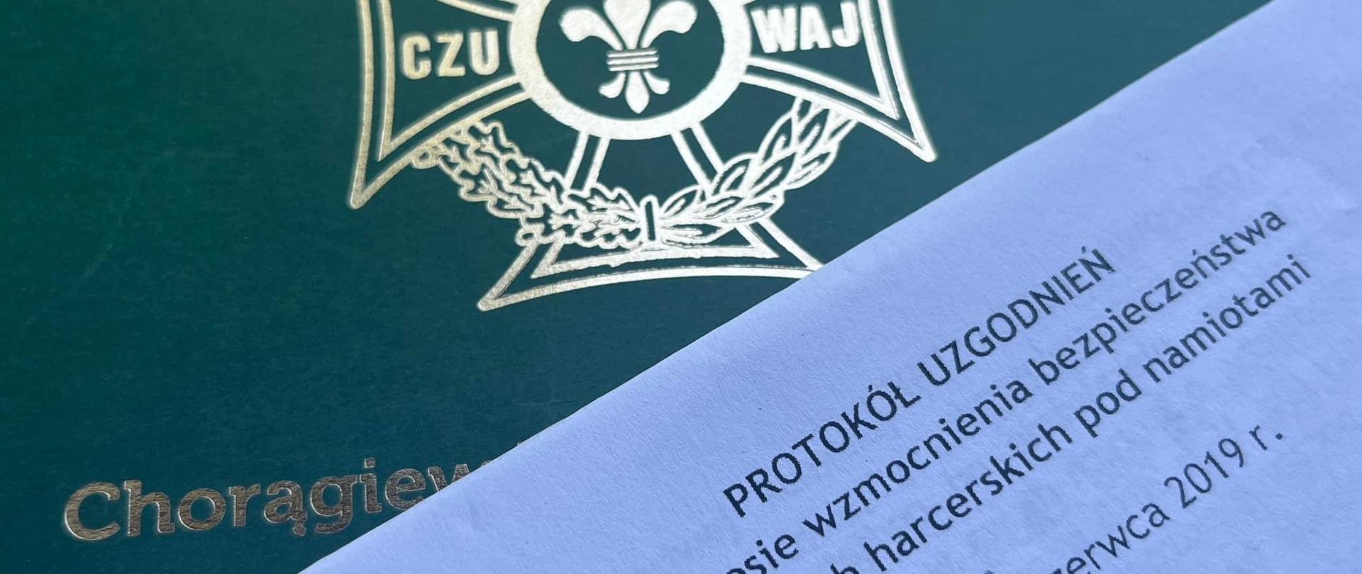 Zdjęcie stronicy tekstu... W tle zielona okładka dokumentu ze znakiem ZHP