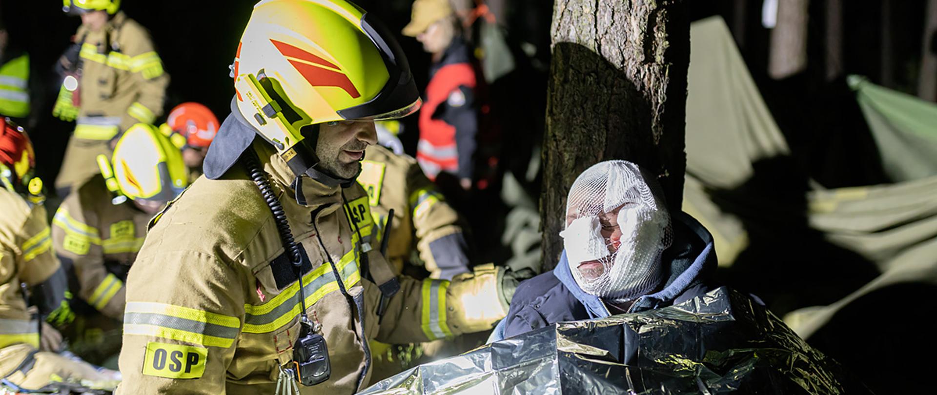 Zdjęcie obrazuje strażaka monitorującego stan zdrowia pozoranta biorącego udział w ćwiczeniach "MOCZARY 2023"