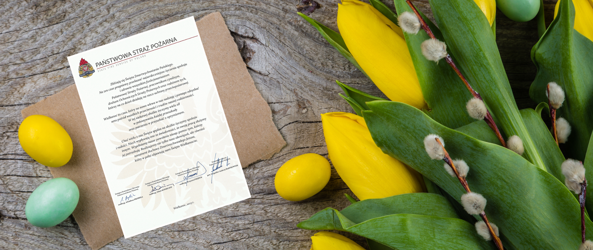 List z życzeniami kierownictwa Państwowej Straży Pożarnej w towarzystwie pisanek, bukietu tulipanów oraz gałązek z baziami