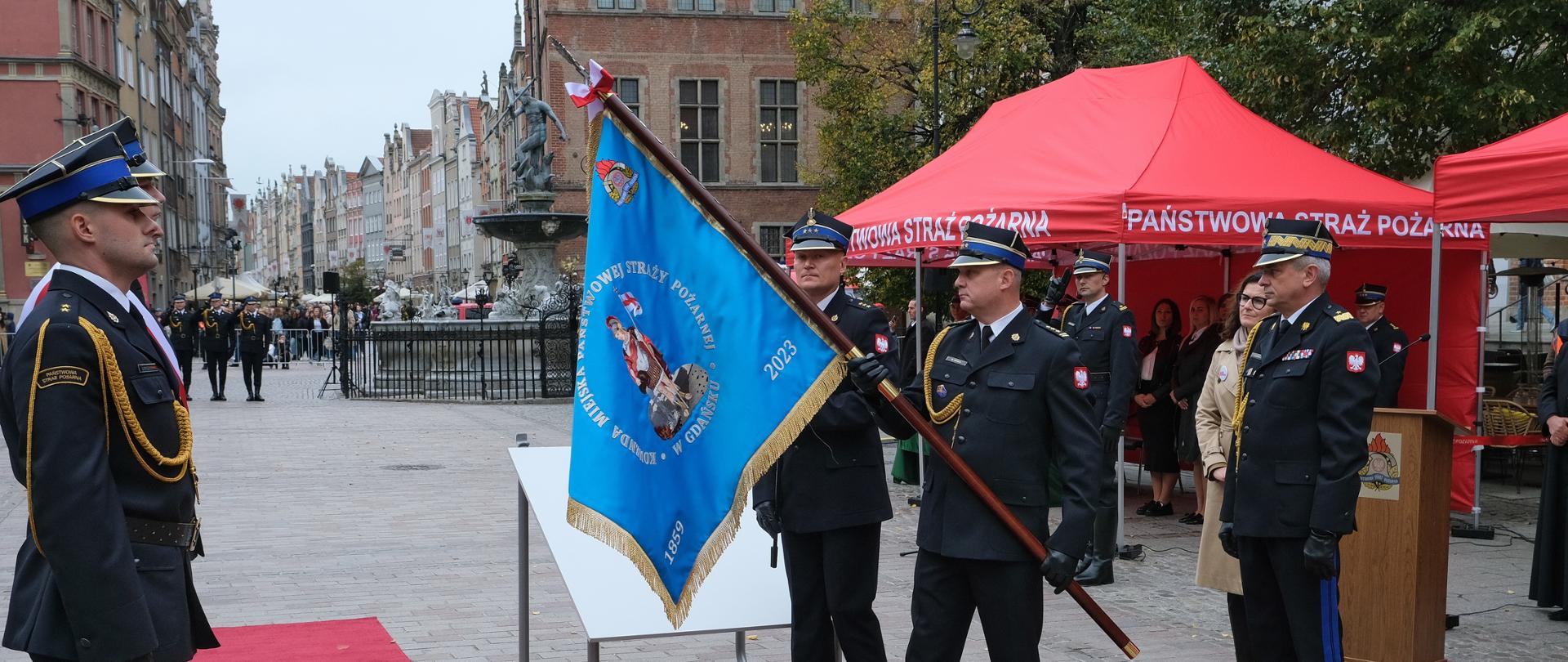 Komendant Miejski PSP w Gdańsku prezentuje sztandar na Długim Targu