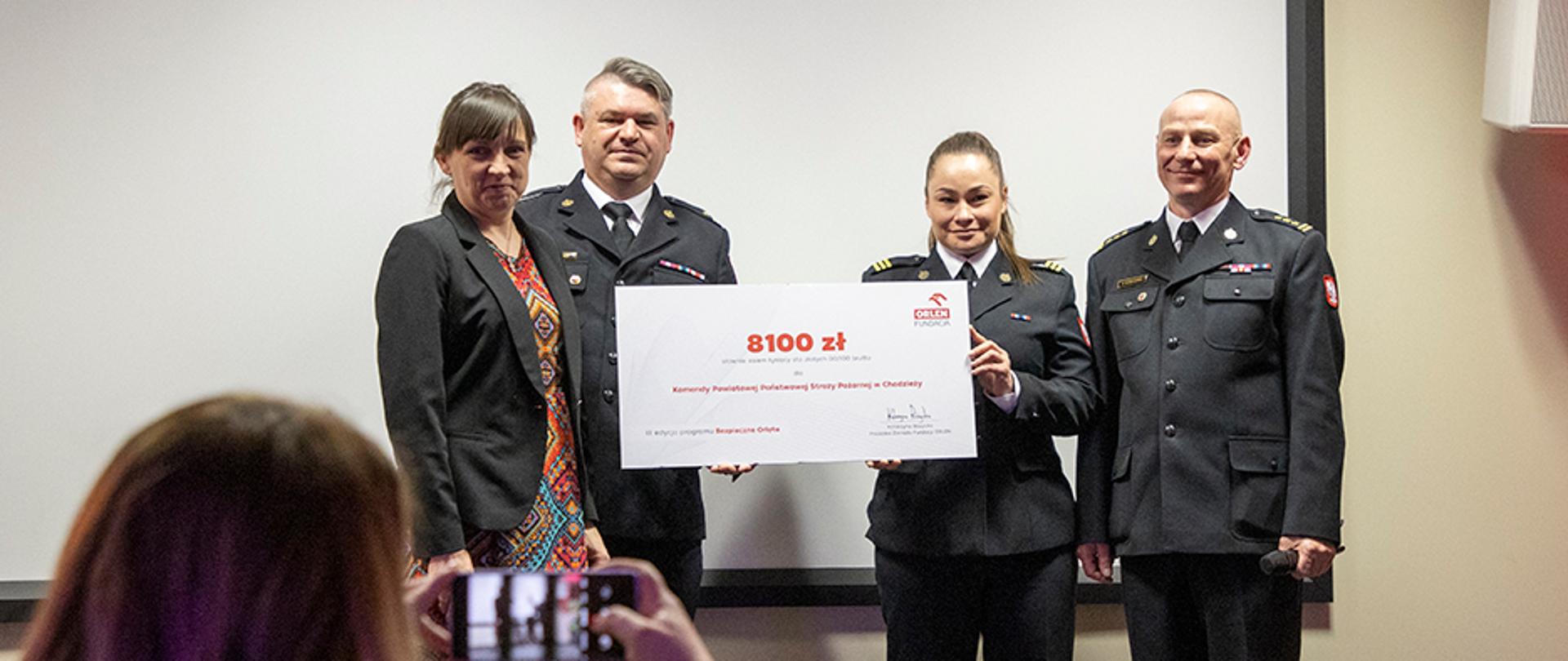 Zdjęcie przedstawia strażaków i przedstawicieli ORLEN oraz wręczających w trakcie uroczystego wręczania promes na zakup doposażenie salek edukacyjnych w potrzebny sprzęt dla Komend PSP.
W tle pomieszczenie Centrum Edukacji i Historii Warszawskiej Straży Pożarnej w Warszawie.
