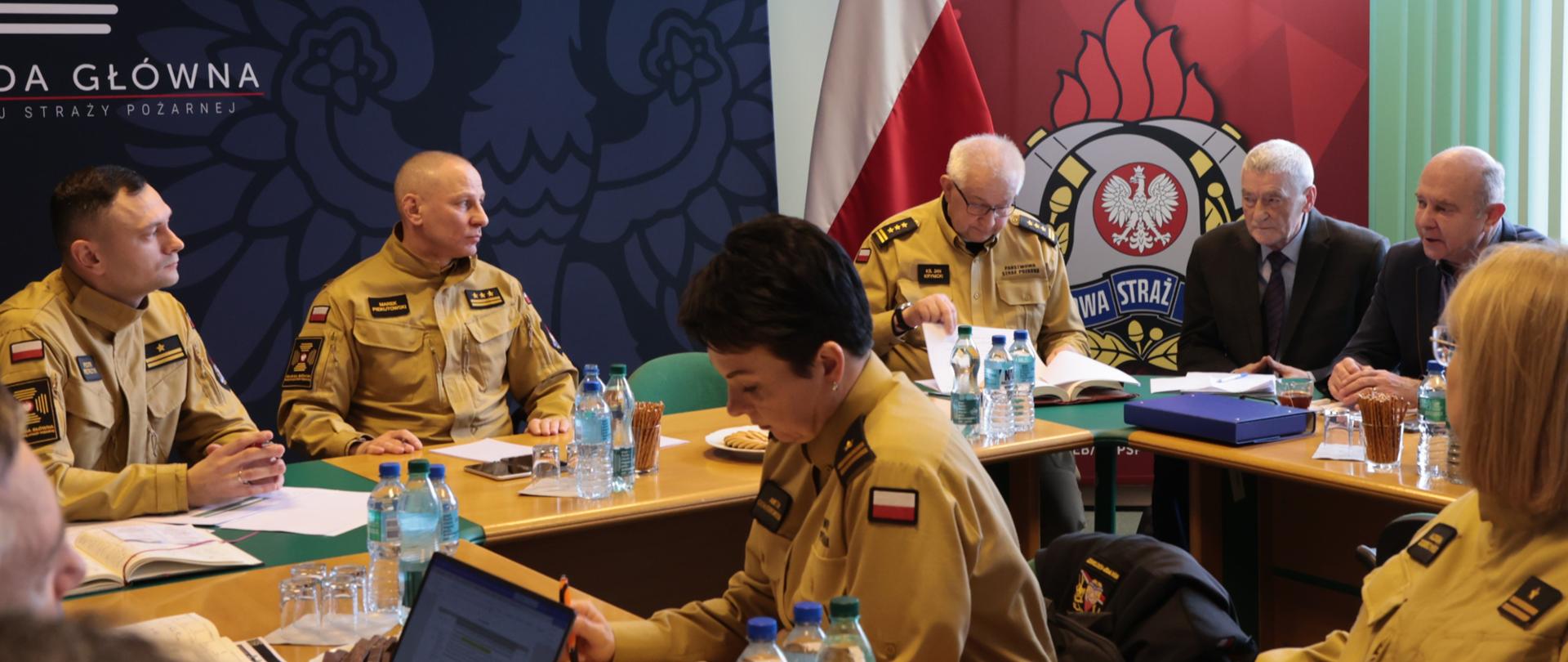 Uczestnicy spotkania siedzący przy stolikach w sali konferencyjnej. 