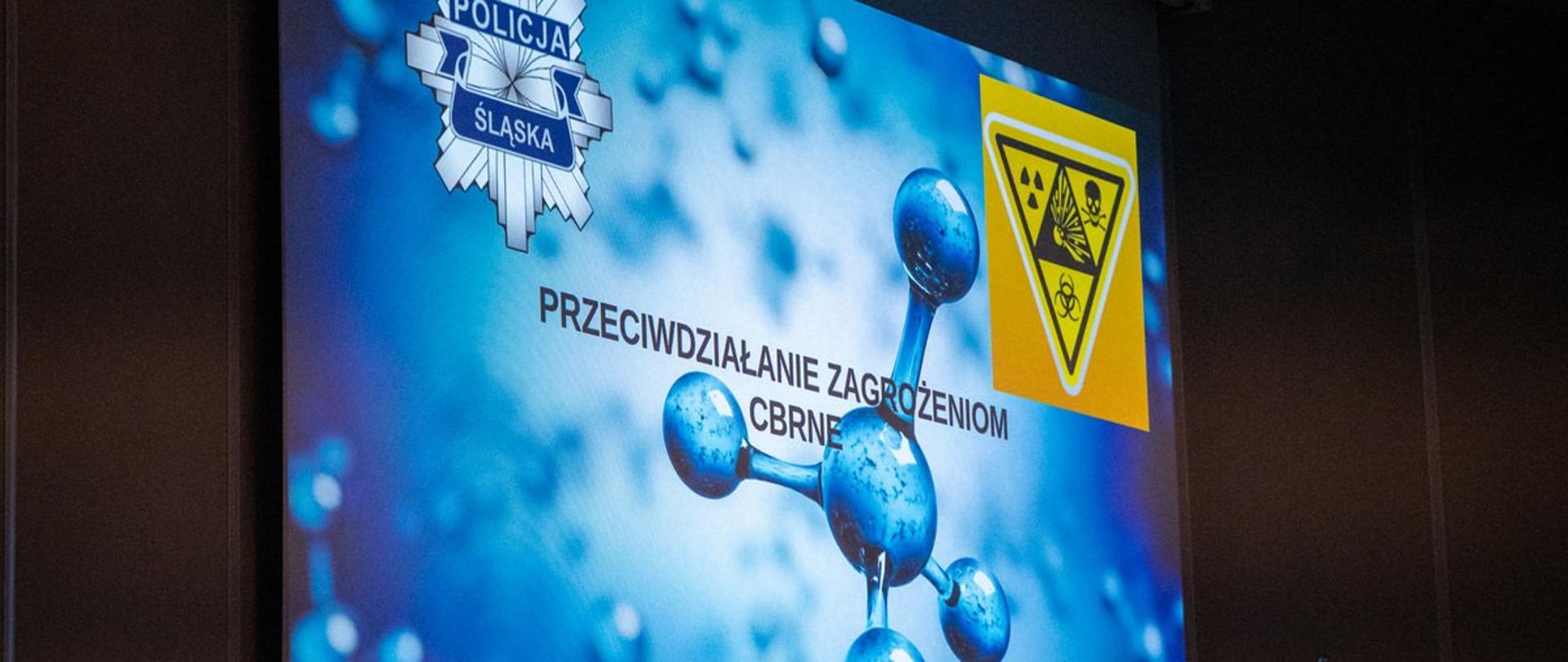 Ekran multimedialny z wyświetlonym tytułowym slajdem prezentacji "Przeciwdziałanie zagrożeniom CBRNE"