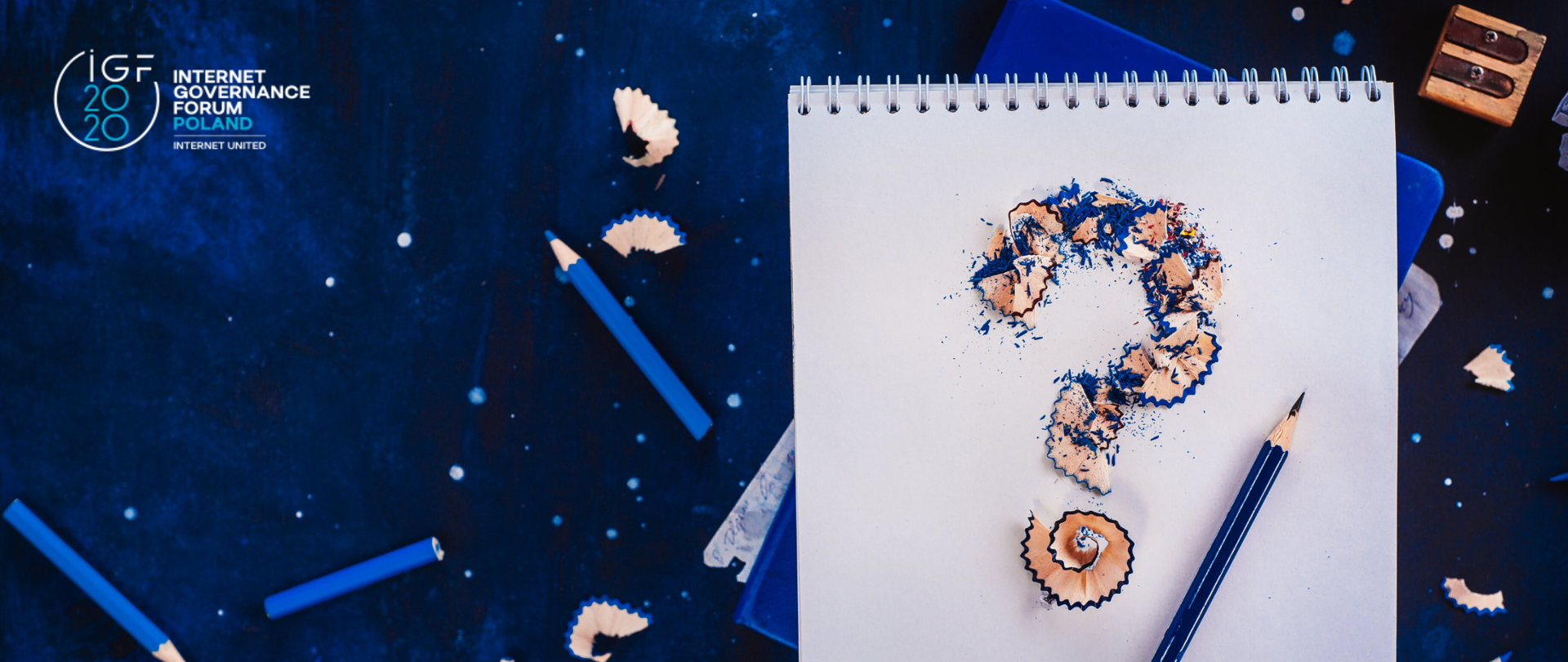Granatowe tło. w Lewym górnym rogu logotyp IGF2020. Po prawej stronie obrazka duży biały kołonotatnik. Wokół niego połamane niebieskie kredki i ścinki od ostrzenia. Na białej kartce ułożone w znak zapytania ścinki i ołówek. Powyżej temperówka.