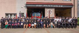 wszyscy uczestnicy uroczystości pozują do zdjęcia na tle budynku remizy OSP Przesiadłów