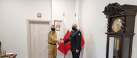 Pomorski komendant wojewódzki Państwowej Straży Pożarnej gratuluje strażakowi, wręczając awans na stanowisko naczelnika wydziału.