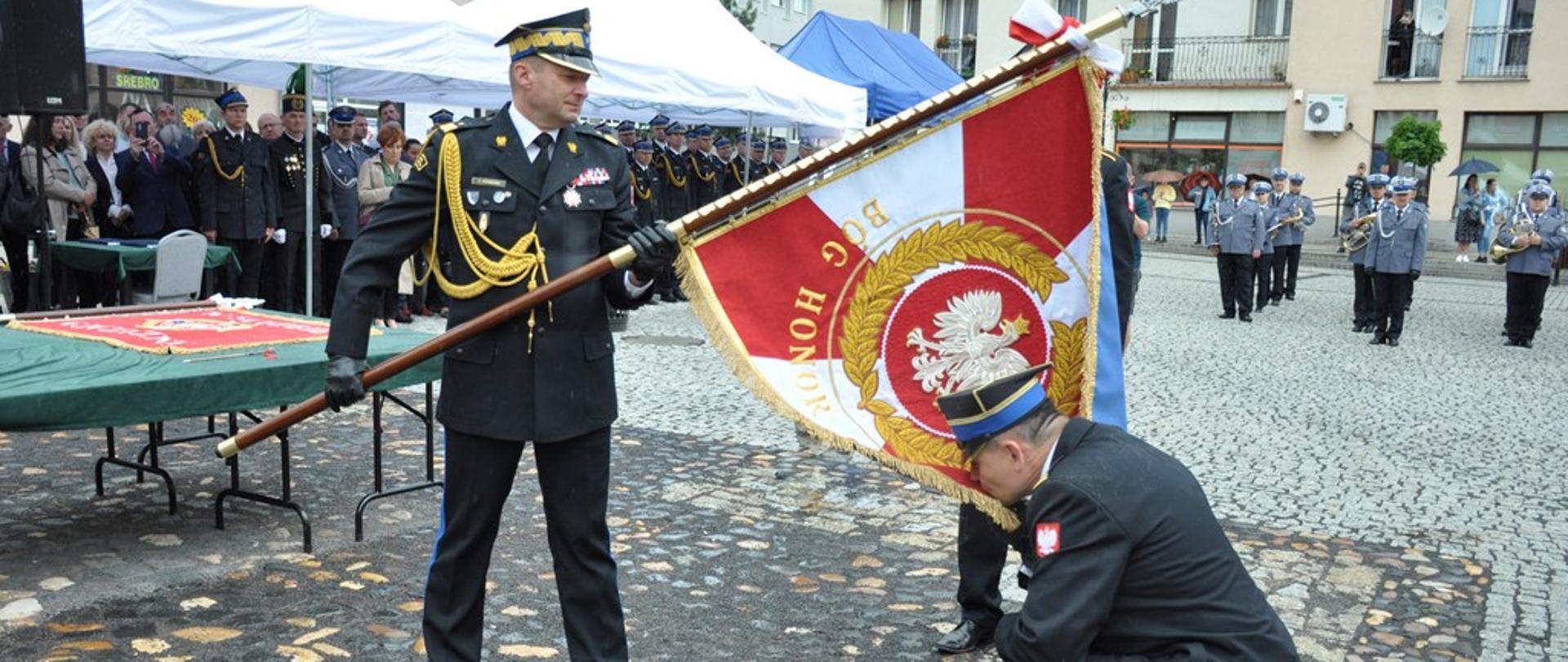 Zdjęcie przedstawia Zastępcę Komendanta Głównego Państwowej Straży Pożarnej nadbrygadiera Adama Koniecznego oraz Komendanta Powiatowego Państwowej Straży Pożarnej w Lwówku Śląskim starszego brygadiera Mariusza Mróz podczas ceremonii przekazania sztandaru dla Komendy Powiatowej Państwowej Straży Pożarnej w Lwówku Śląskim. 