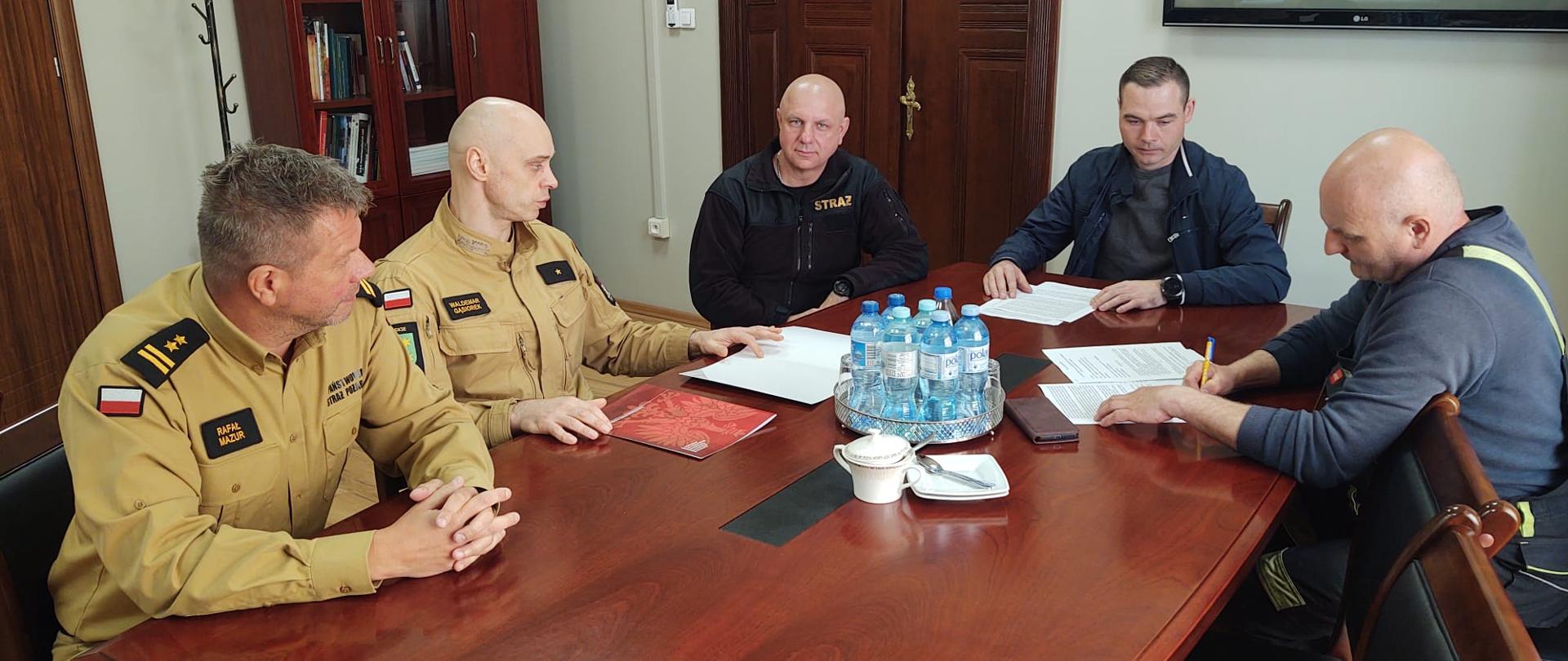 Strażacy i przyszli kierowcy OSP przy jednym stole w biurze 