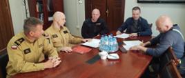strażacy i przyszli kierowcy OSP przy jednym stole w biurze