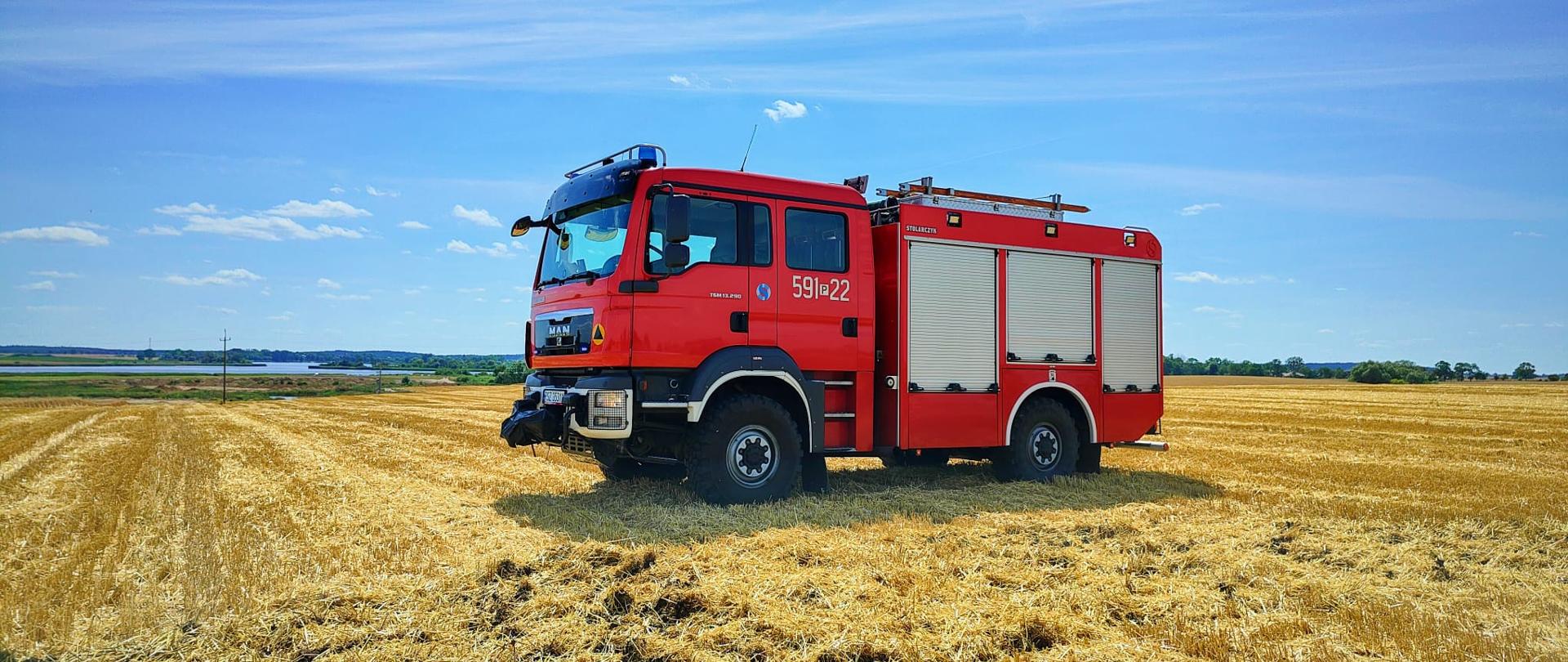 Czerwony samochód strażacki znajduje się na ściernisku