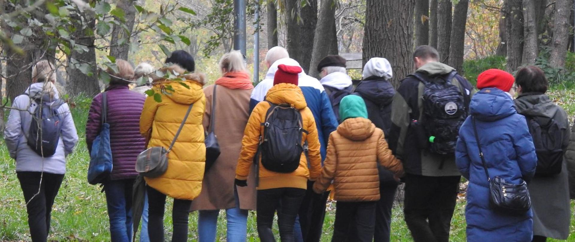 Grupa ludzi idąca pośród drzew.