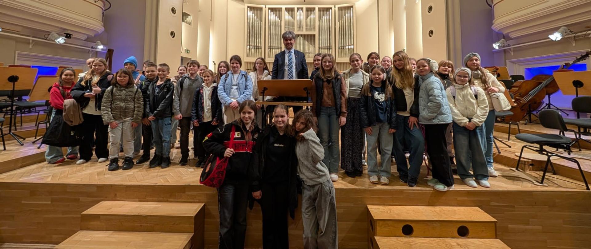 Grupa chórzystów z dyrygentem Jarosławem Wolaninem