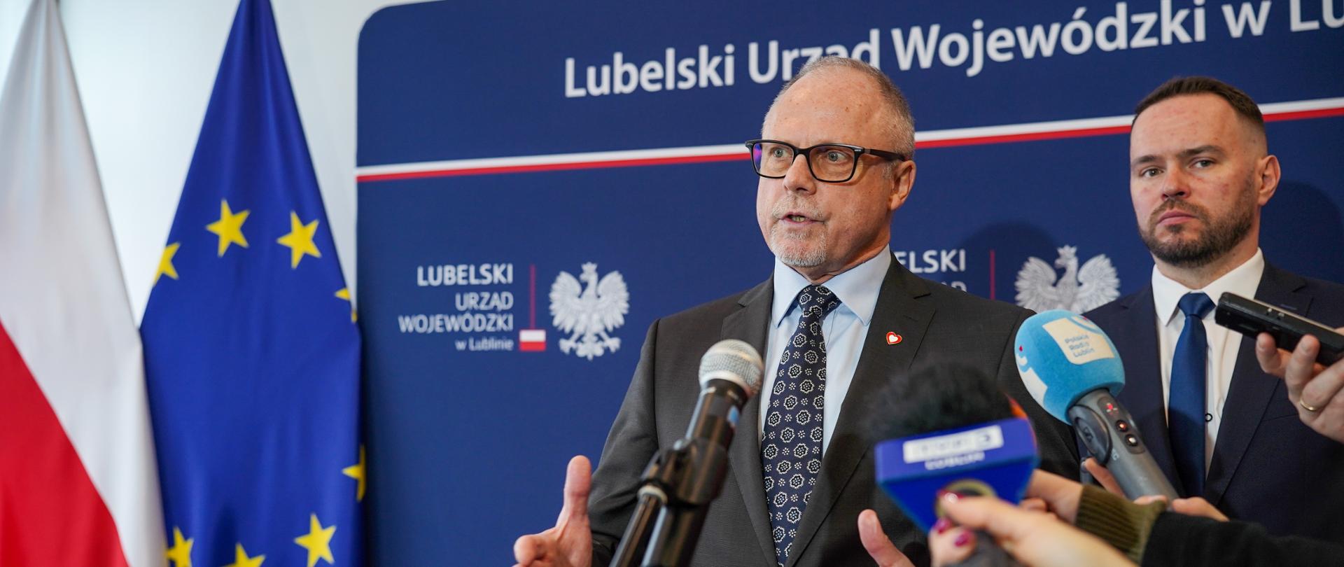 Wiceminister Jacek Protas i wojewoda Krzysztof Komorski przed mikrofonami na briefingu prasowym