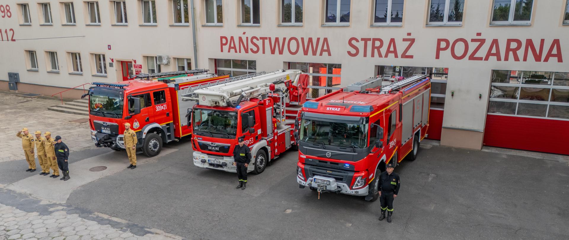 Strażacy stojący na baczność przed budynkiem jednostki oddają hołd uczestnikom powstania warszawskiego