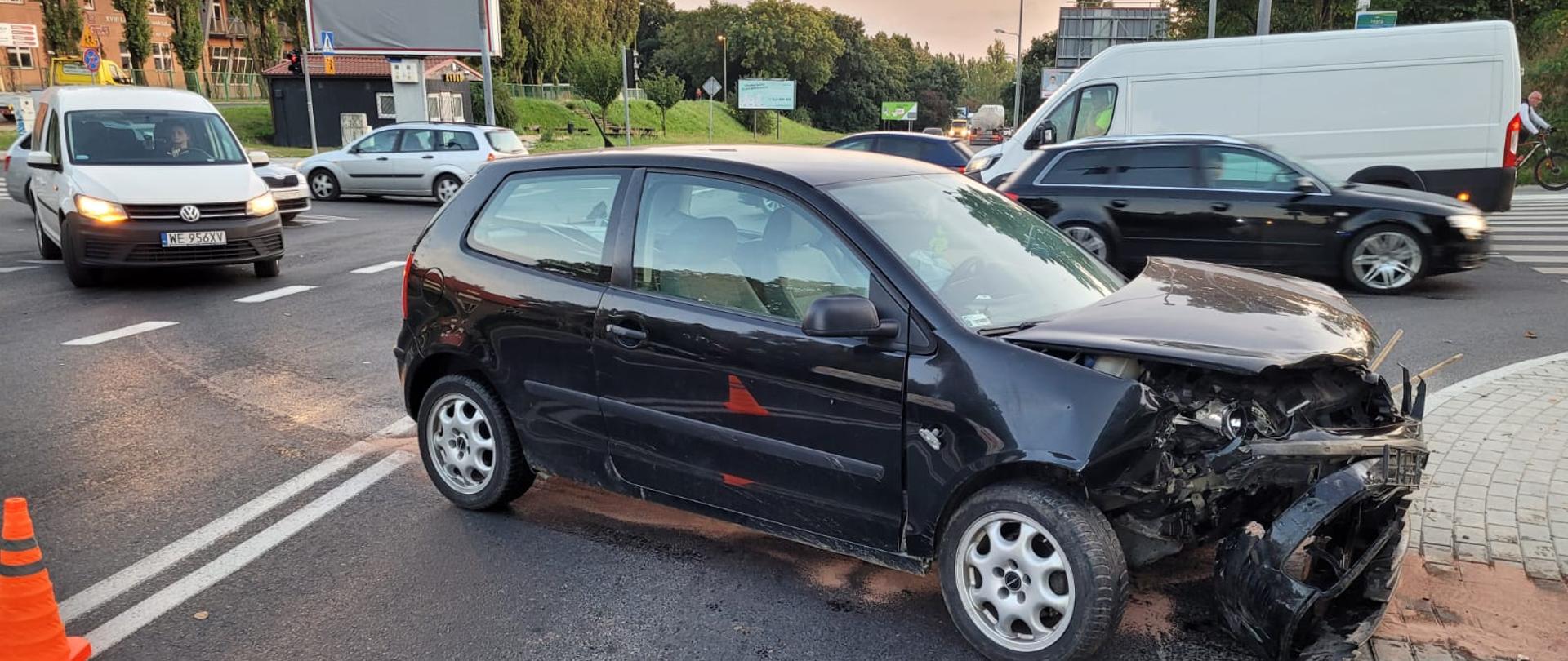 Samochód osobowy z uszkodzonym przodem w wyniku wypadku, w tle ruch samochodów osobowych na ul. Hożej.