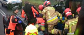 Strażacy z ratownikami medycznymi podczas działań przy wypadku.