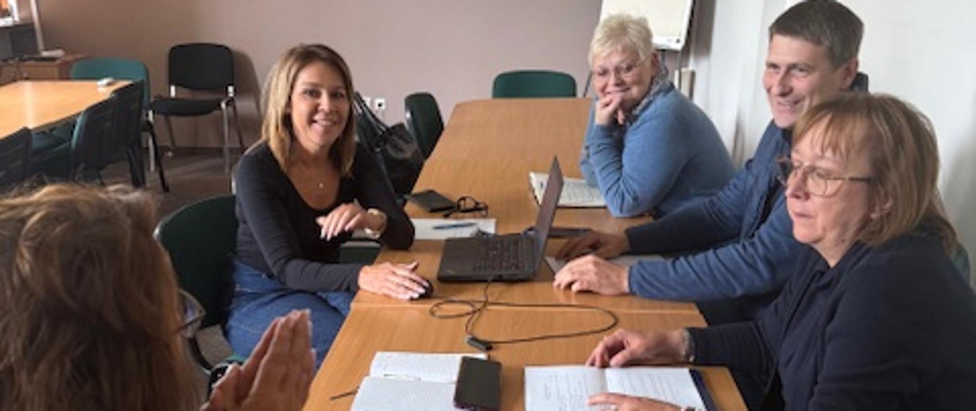 Grupa osób: cztery kobiety i jeden mężczyzna rozmawiający przy stole