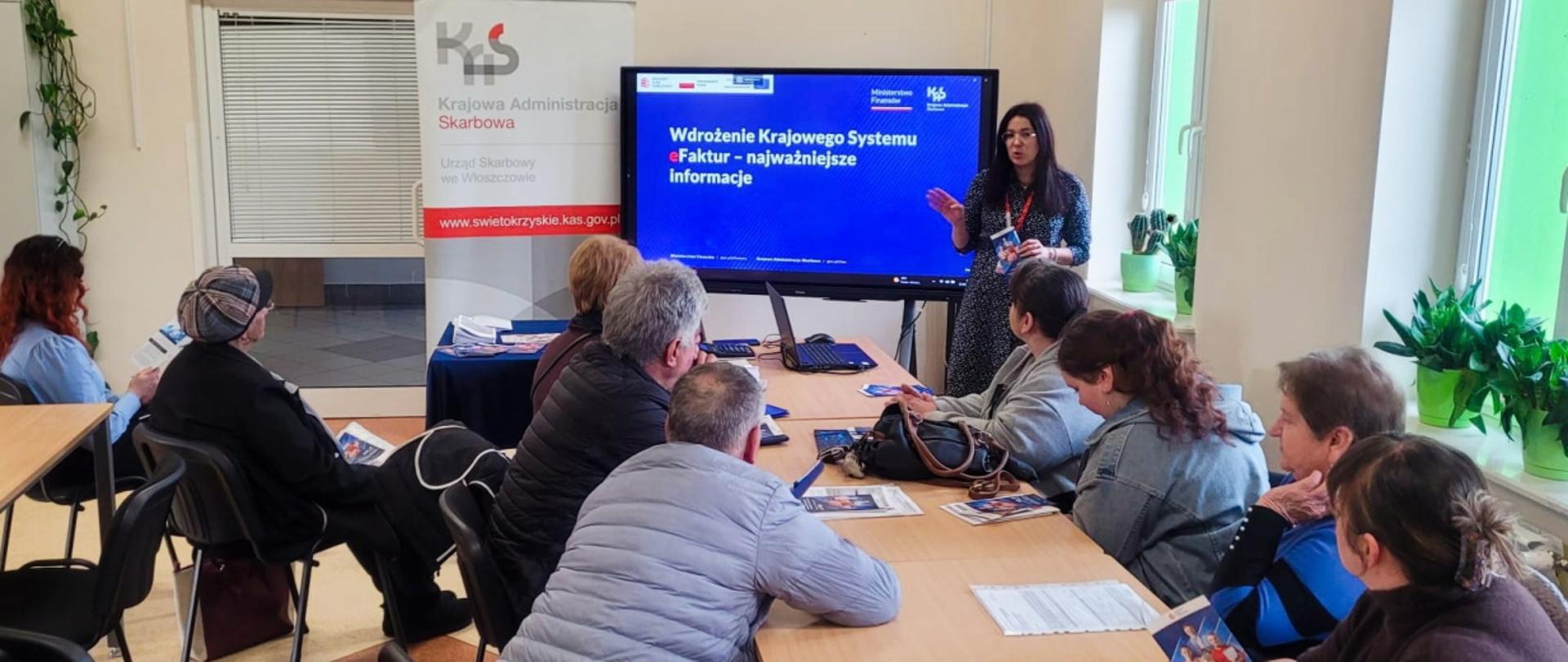 Przy stole siedzi grupa osób