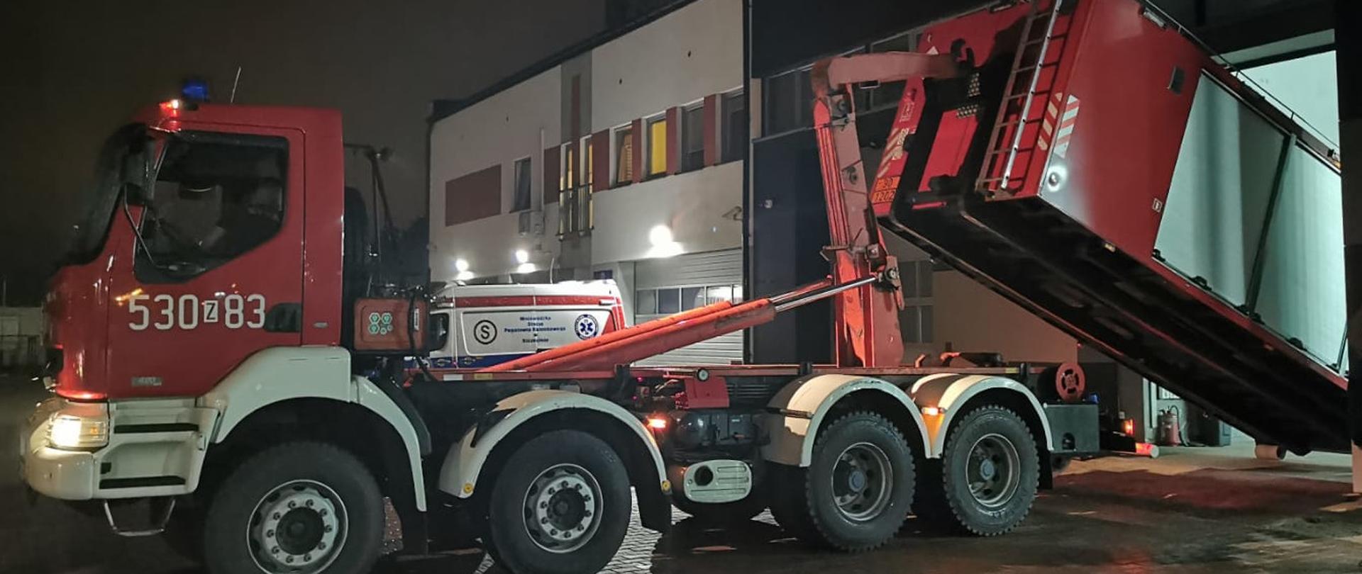 Samochód do przewozu kontenerów podczas załadunku kontenera z garażu.