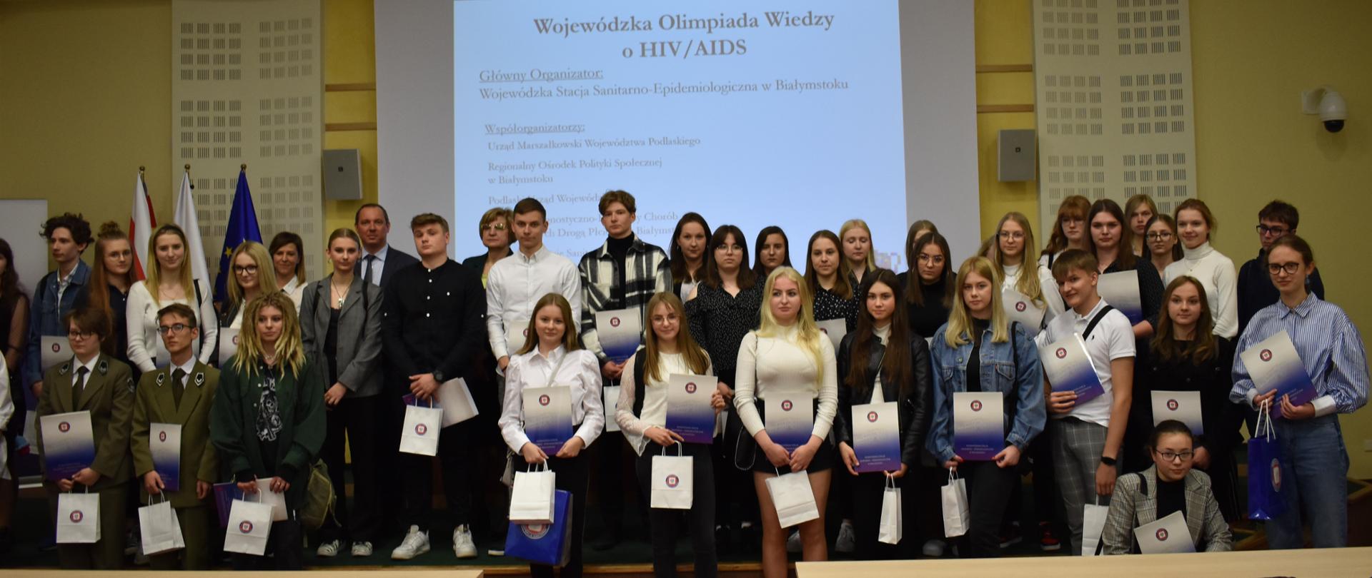 Zdjęcia przedstawiają uczestniczki i uczestników olimpiady, młodzież ze szkół ponadpodstawowych województwa podlaskiego, podczas zmagań przy pisaniu testu w czasie trwania olimpiady w Sali konferencyjnej Urzędu Marszałkowskiego w Białymstoku. 