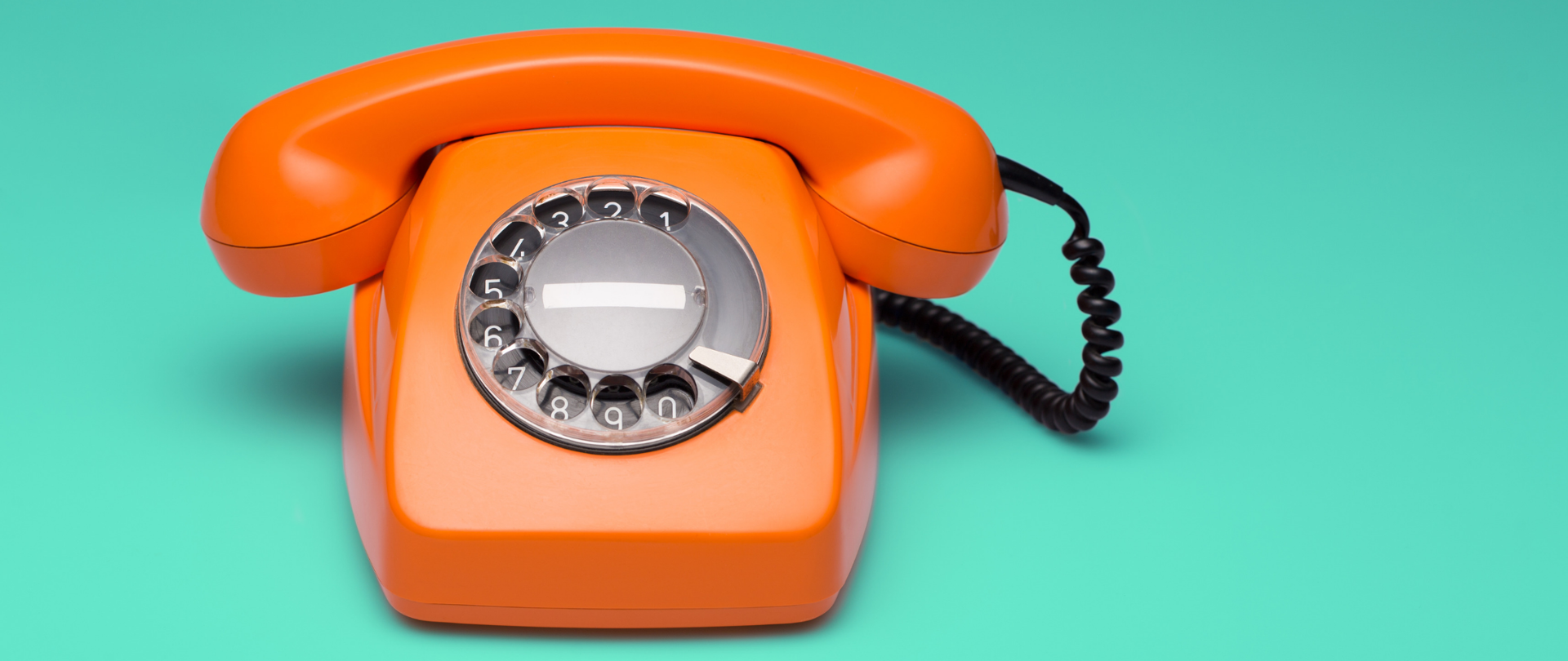 Stary pomarańczowy telefon z tarczą numerową, zielone tło