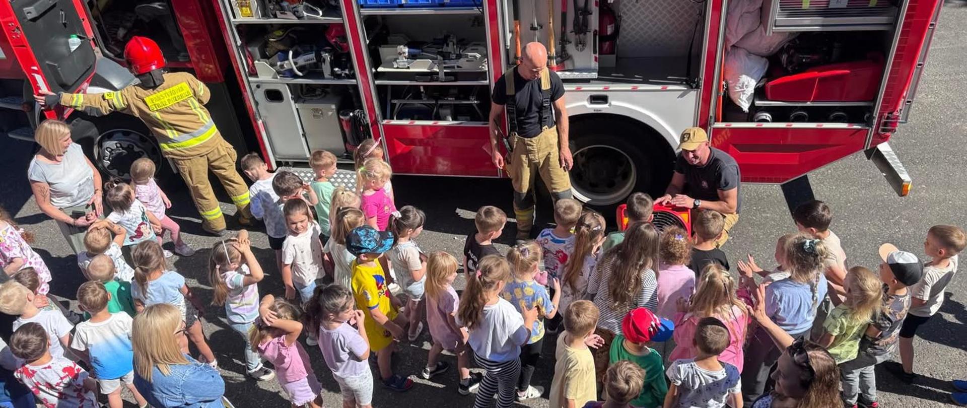 Przedszkolaki oglądają wyposażenie samochodu strażackiego