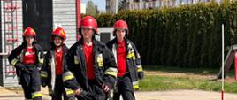 Czterech uczestników na placu przed wspinalnią PSP przebranych w mundury strażackie 