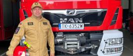 Dariusz Kroczak na tle samochodu gaśniczego. 