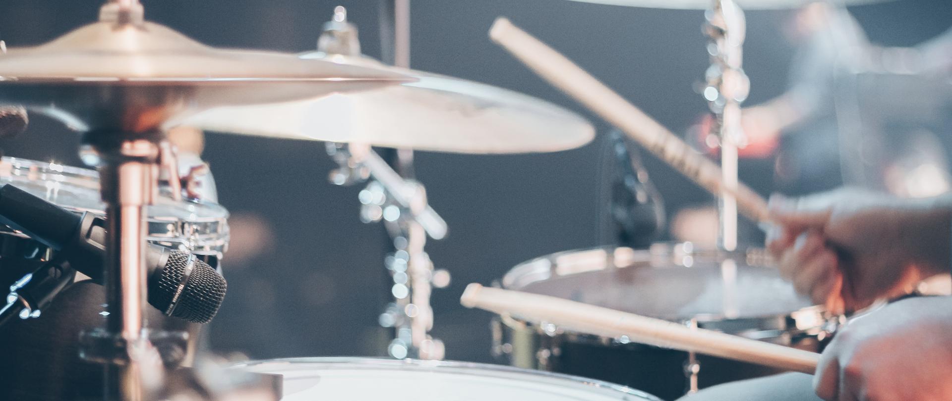 talerze perkusyjne, werbel oraz dłonie trzymające pałeczki perkusyjne