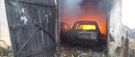 Zdjęcie przedstawia spalone samochody osobowe znajdujące się budynku gospodarczym