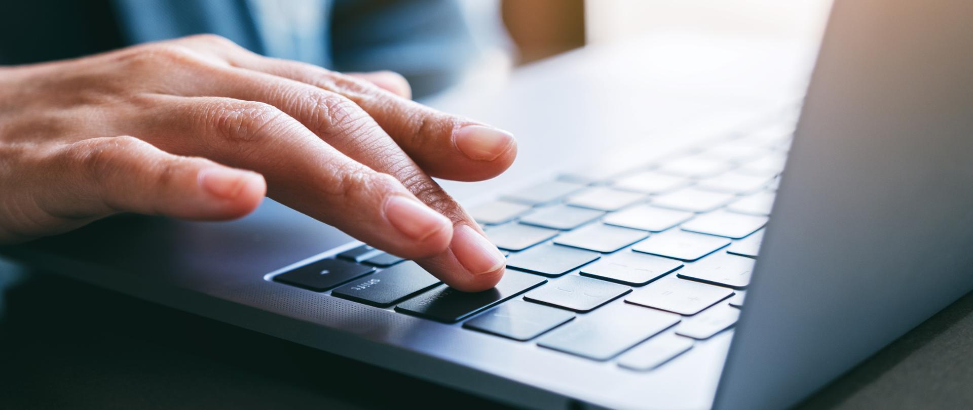 Dłoń na klawiaturze laptopa