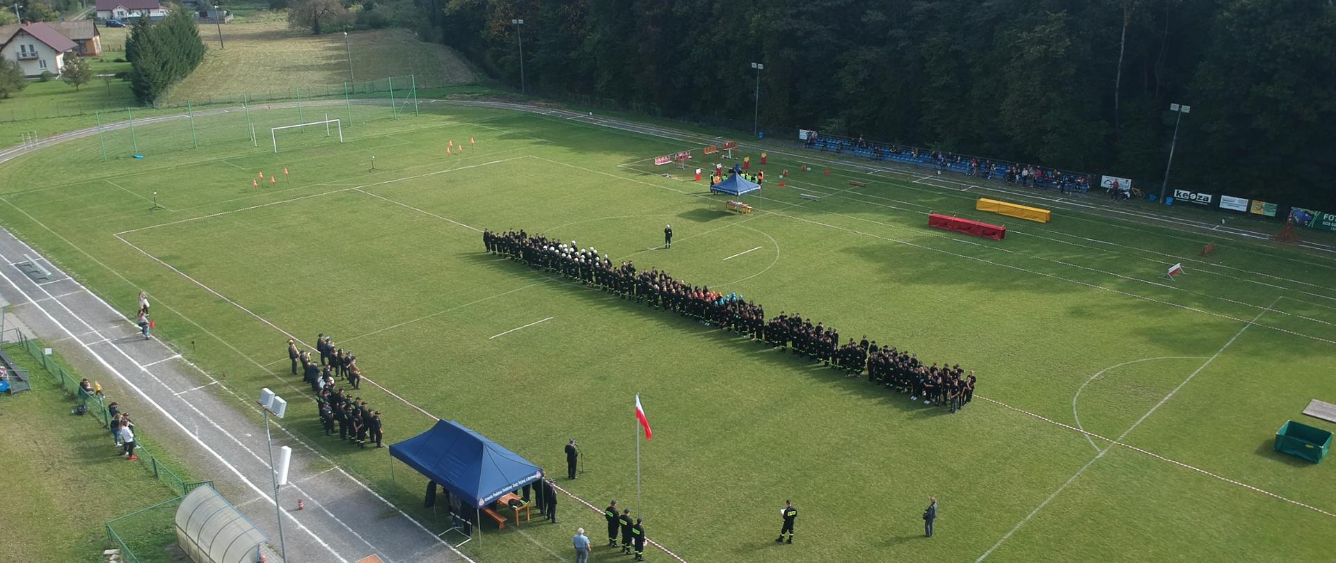 Zbiórka uczestników przed rozpoczęciem zawodów na boisku sportowym