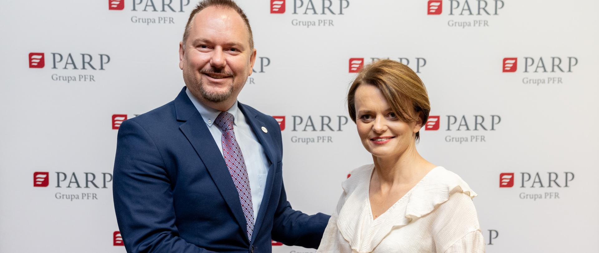 Dwie osoby ściskają sobie dłonie. Pierwsza z prawej to wiceminister Jadwiga Emilewicz.