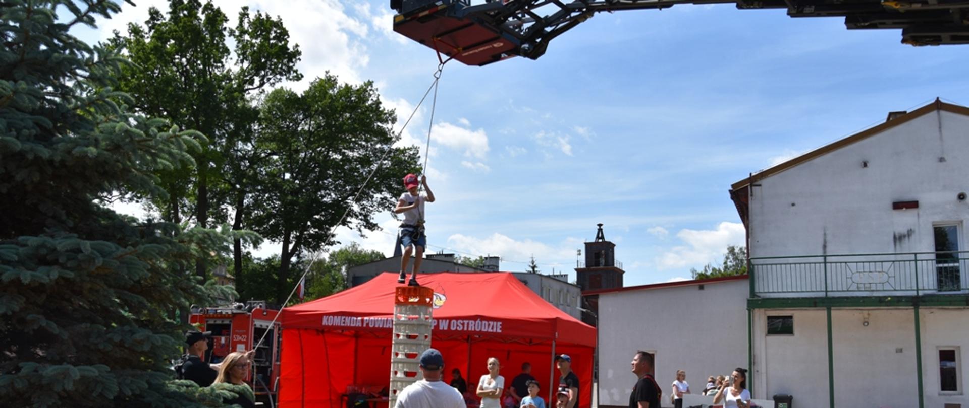 Chłopiec wspina się na torze przeszkód. 