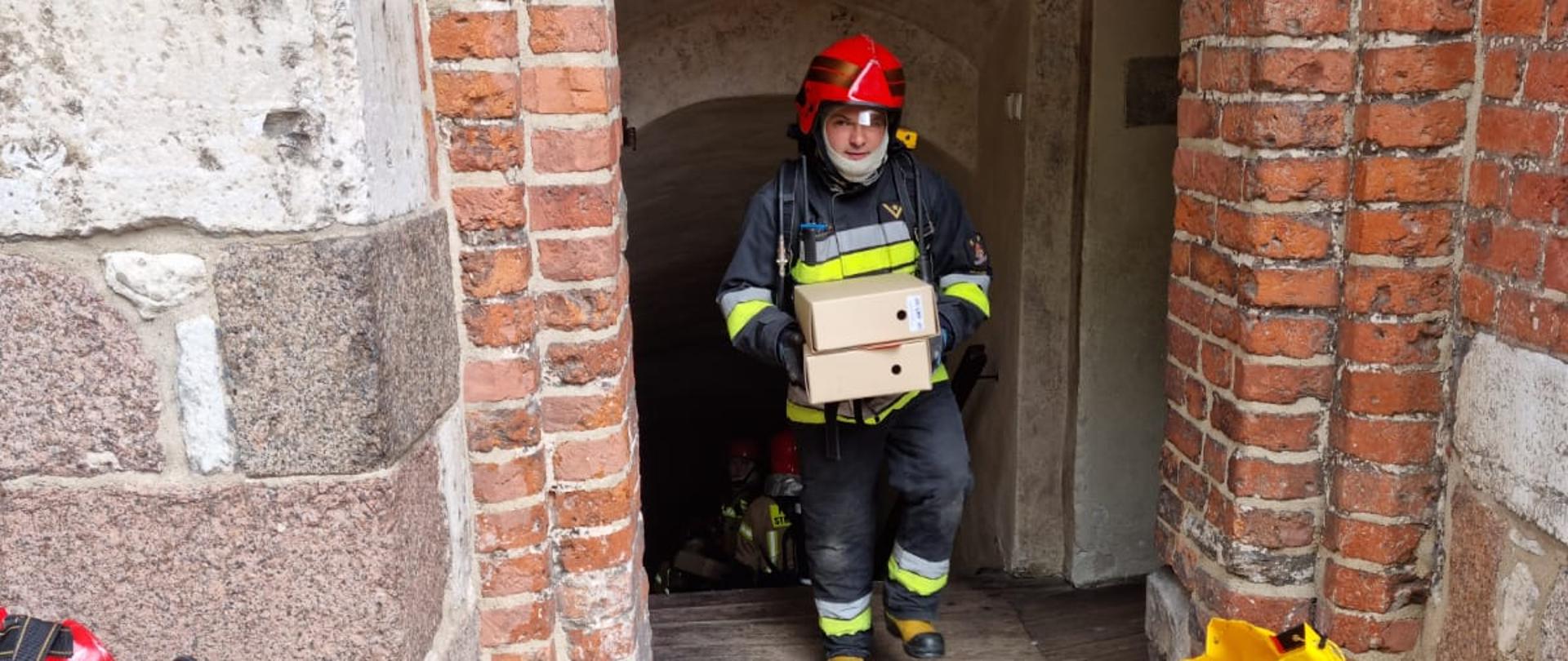 Fotografia przedstawia strażaka podczas ewakuacji mienia z Archiwum Państwowego