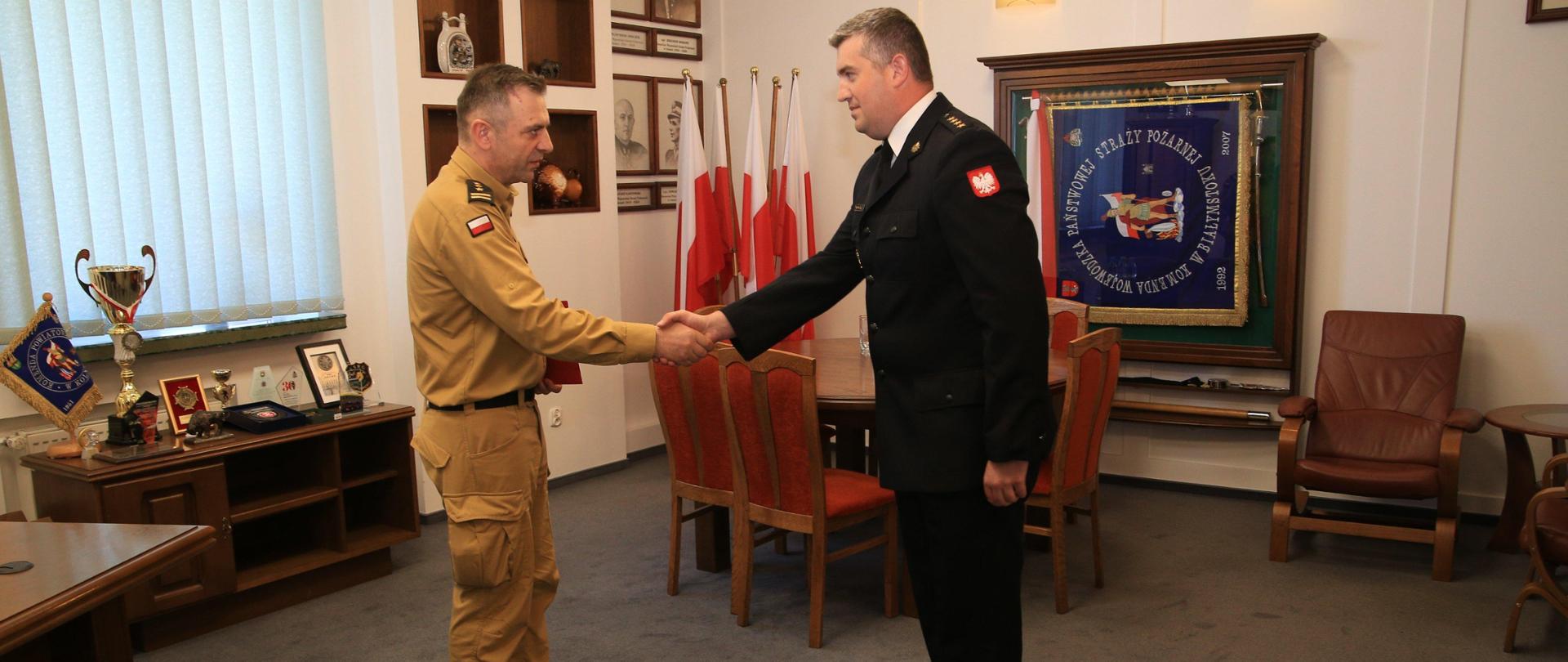 Podlaski Komendant Wojewódzki przez uścisk dłoni gratuluje strażakowi powierzenia pełnienia obowiązków na stanowisku zastępcy komendanta miejskiego PSP