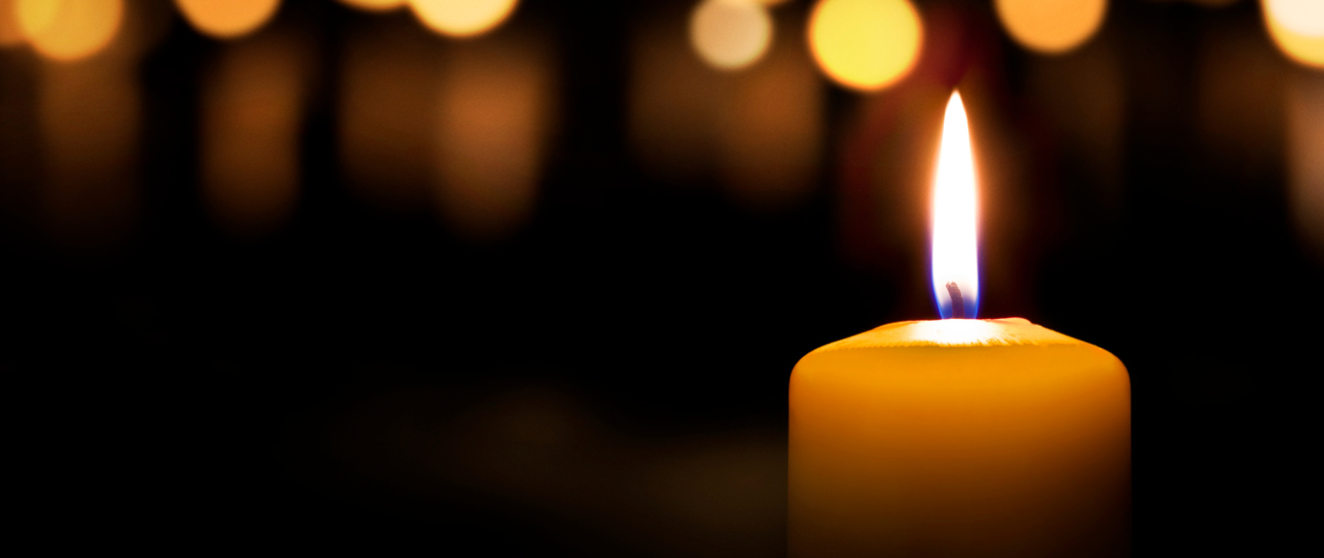 Zapalona świeca, czarne tło.